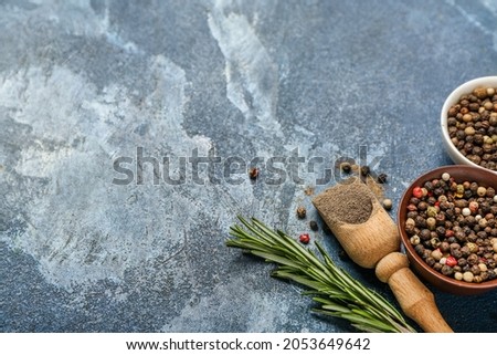 Black pepper powder and peppercorns on color background