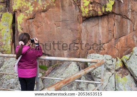 Little girl taking pictures to San Blas rock shelter with prehistorical paintings. Alburquerque, Badajoz, Extremadura, Spain