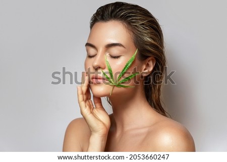 CBD cosmetics concept. Beautiful woman with a cannabis leaf on gray background Royalty-Free Stock Photo #2053660247