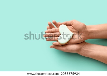 Hands with heart-shaped cookie on color background Royalty-Free Stock Photo #2053675934