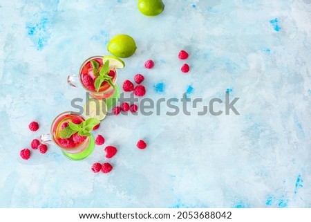 Cups of cold raspberry tea on color background