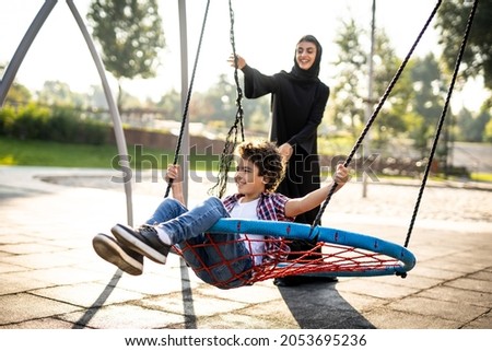Cinematic image of a woman from the emirates with her children having fun at the playground Royalty-Free Stock Photo #2053695236