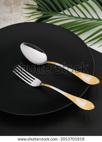 A set of cutlery on a dark background using various props.