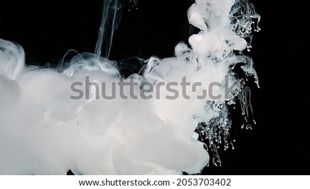 White abstract background. Waves of milky ink and splashes of white paints in the water. White watercolor ink in water on a black background. Black and white fantastic art.