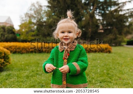 portrait of a happy little girl in autumn clothes. the child laughs against the background of nature.