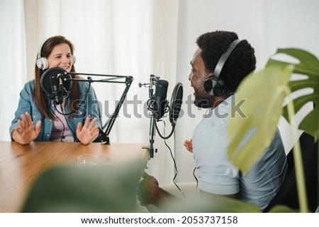 Diverse colleagues recording podcast and talking in microphones