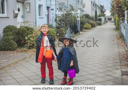 Halloween. Adorable boy and girl dressed as witch and dracula with buckets of pumpkins. Autumn.