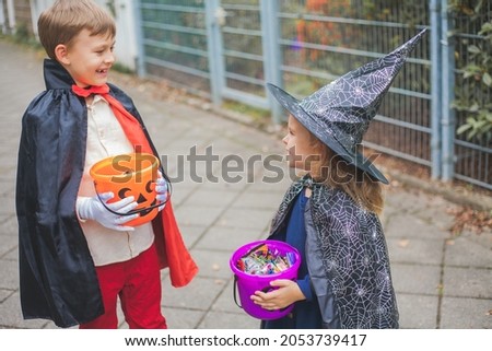 Halloween. Adorable boy and girl dressed as witch and dracula with buckets of pumpkins. Autumn.