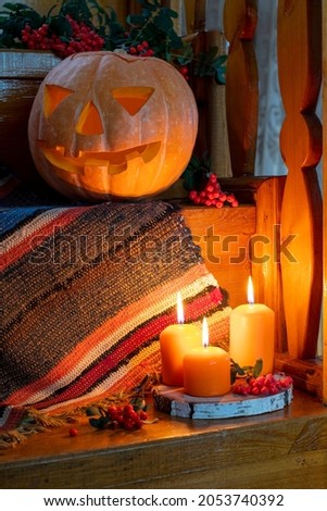 Halloween concept. Rustic Halloween card. Happy Halloween. Jack's lantern from pumpkin and candles. Pumpkin with a cut out face. Candles and rowan clusters around. Copy space. Selective focus.
