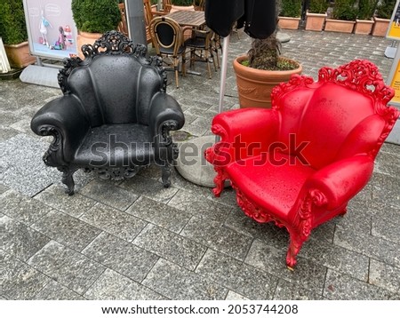 Black and red chair on the street in Vaduz in Liechtenstein. Arm chairs are near the food shop on the main street under the rock with castle. The castle is seat of the rulling family. Switzerland.