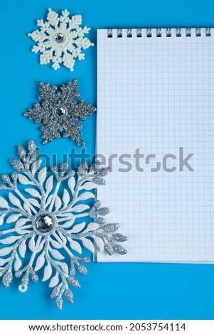 Notebook and snowflakes on a blue background. Christmas decor. Place for your text.