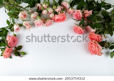 Pink roses on a light wooden background, place for your text. Flowers border.