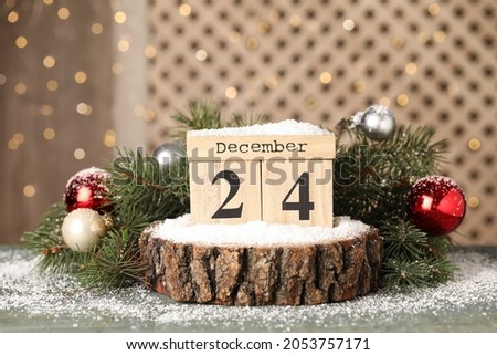 December 24 - Christmas Eve. Wooden block calendar and festive decor on grey table Royalty-Free Stock Photo #2053757171