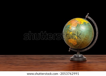 Earth globe on a table. Wood and black background