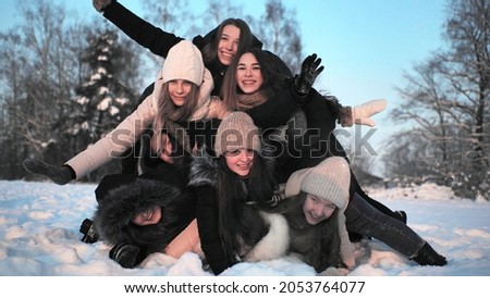 Cheerful girls fall on each other in the snow.