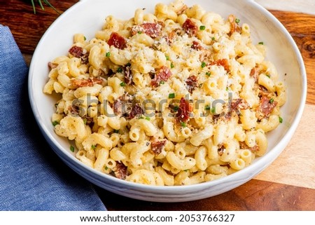 Macaroni and cheese. Macaroni mixed with melted cheddar cheese, grilled Cajun shrimp, crispy bacon, jalapeños, spicy corn salsa, and cilantro. Classic American bar appetizer, loaded Mac n cheese.