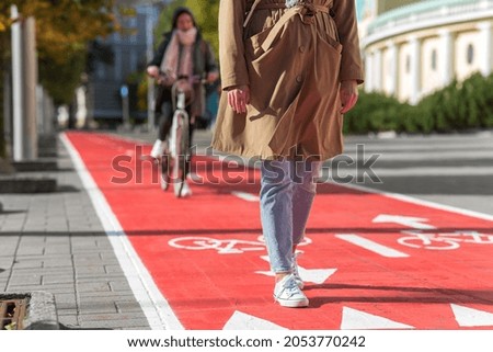 city and traffic concept - close up of woman walking along separate bike lane or red road with signs only for bicycles on street