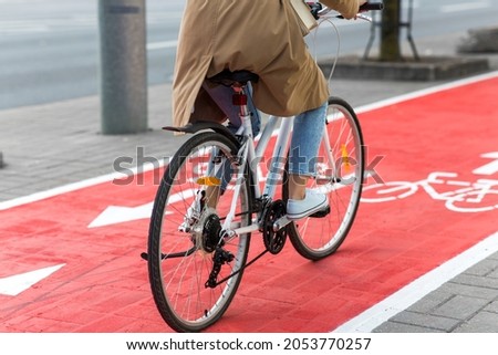 traffic, city transport and people concept - woman cycling along red bike lane with signs of bicycles on street