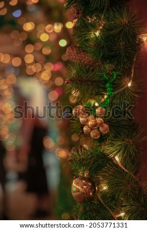 festive Christmas decoration with hanging toy balls and background blurry garland lights, vertical picture, focus on toys