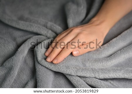 Woman touching grey blanket, close up. Close up of hand touching soft blanket. Gentle and fluffy blanket between fingers. Royalty-Free Stock Photo #2053819829