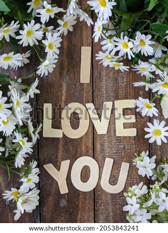 I love you wording on the wooden table with white flowers frame