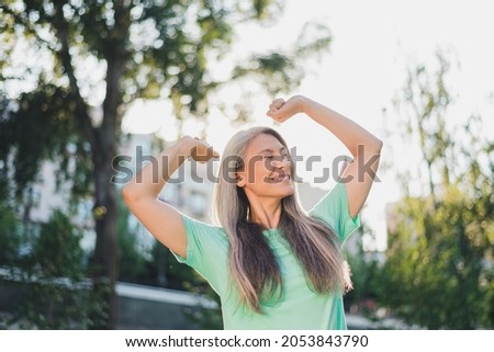Photo of carefree serene peaceful pensioner lady enjoy sunny day stretch wear turquoise t-shirt urban city outside