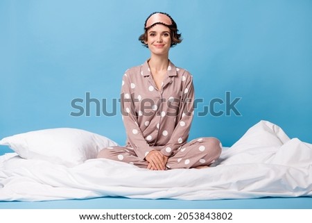 Full length photo of young girl happy positive smile sit bed wear pajamas isolated over blue color background Royalty-Free Stock Photo #2053843802