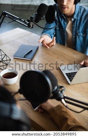 cropped view of radio hosts talking in microphone during podcast
