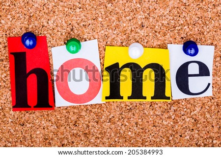 The word Home in cut out magazine letters pinned to a cork notice board