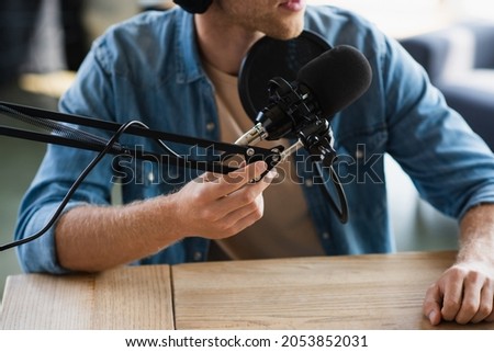 cropped view of influencer touching scissor arm near microphone while making podcast in studio