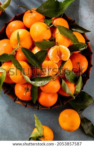 Fresh mandarin oranges fruit with leaves in wooden box, top view.