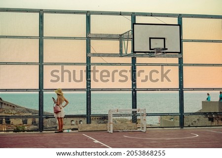 Young traveler girl play basketball inside the fortress with sea on the background. Popular tourist destination, tourists take pictures of medieval fortification. Gorgeous stone building in Dubrovnik