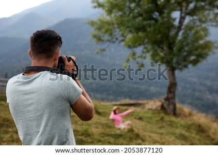 Professional photographer taking picture of woman in mountains, back view