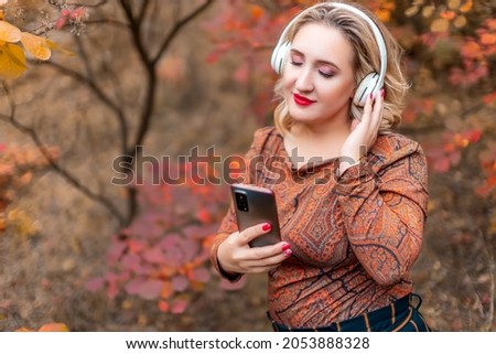 a young woman on the background of an autumn park has closed her eyes and is listening to music