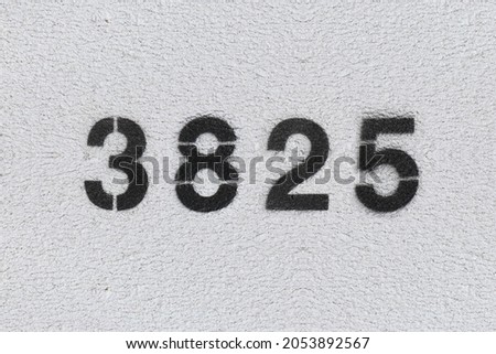Black Number 3825 on the white wall. Spray paint. Number three thousand eight hundred and twenty five.