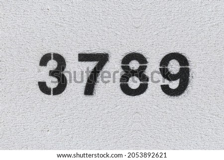 Black Number 3789 on the white wall. Spray paint. Number three thousand seven hundred and eighty nine.
