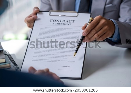 Real estate agent home sales broker is using a pen pointing to the contract document house model and explains the business contract, rent, buy, mortgage, loan, or home insurance