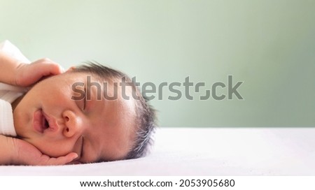 cute newborn baby boy sleeping on the bed at children's bedroom in the morning time with copy space. family, healthy, life and relationship concept