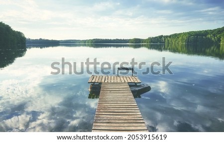 Wooden pier at calm Lipie Lake, color toned picture, Poland.