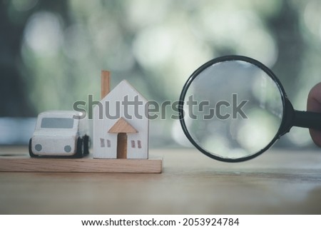 Magnifying glass with a toy house and a car suggesting family investments