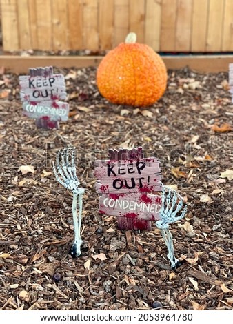 Yard is decorated for Halloween with a makeshift cemetary and pumpkins