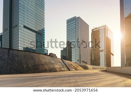 empty concrete ground floor with modern cityscape and buildings during sunrise. Royalty-Free Stock Photo #2053971656