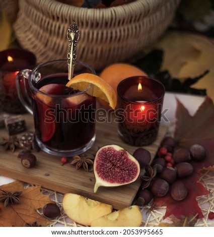 Close up of autumn picnic with food, mulled wine with cinnamon and chocolate on lawn with maple leaves. Romantic dinner in garden in evening outdoors