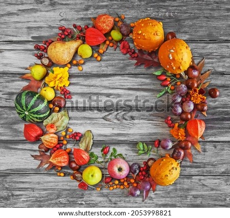 Wreath of autumn fruits, berries and leaves on a wooden background