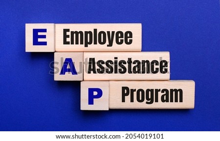 On a bright blue background, light wooden blocks and cubes with the text EAP Employee Assistance Program Royalty-Free Stock Photo #2054019101