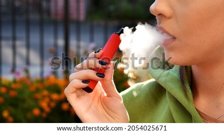 beautiful women smoke electronic cigarette in street Royalty-Free Stock Photo #2054025671