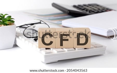 CFD written on wooden cube on keyboard with office tools