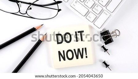 Text DO IT NOW on sticker with keyboard , pencils and office tools