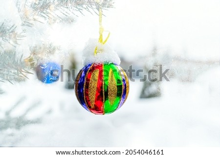 Christmas tree in the snow, a bright rainbow Christmas ball hanging on a tree. Christmas background with copy space.