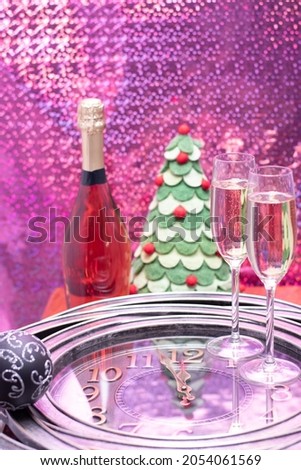 New year party decoration with champagne flutes standing on the clock showing time close to midnight.
